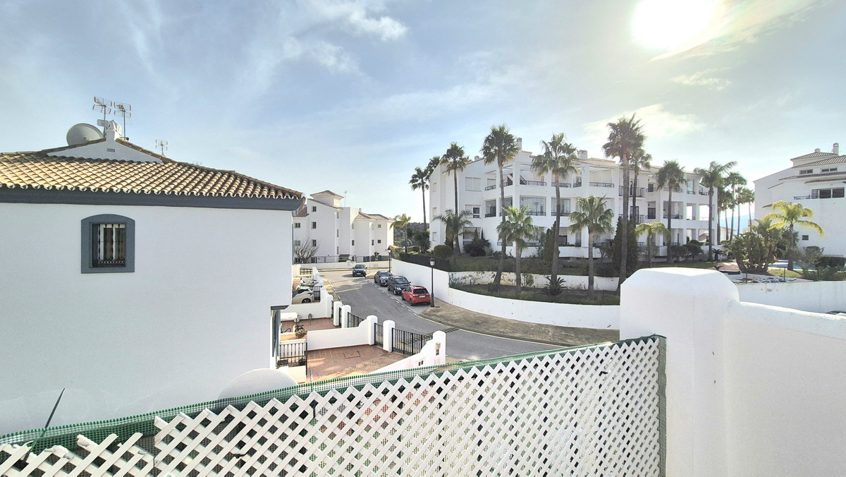 Uitzicht op een mediterraan appartementencomplex met palmbomen vanaf het balkon.
