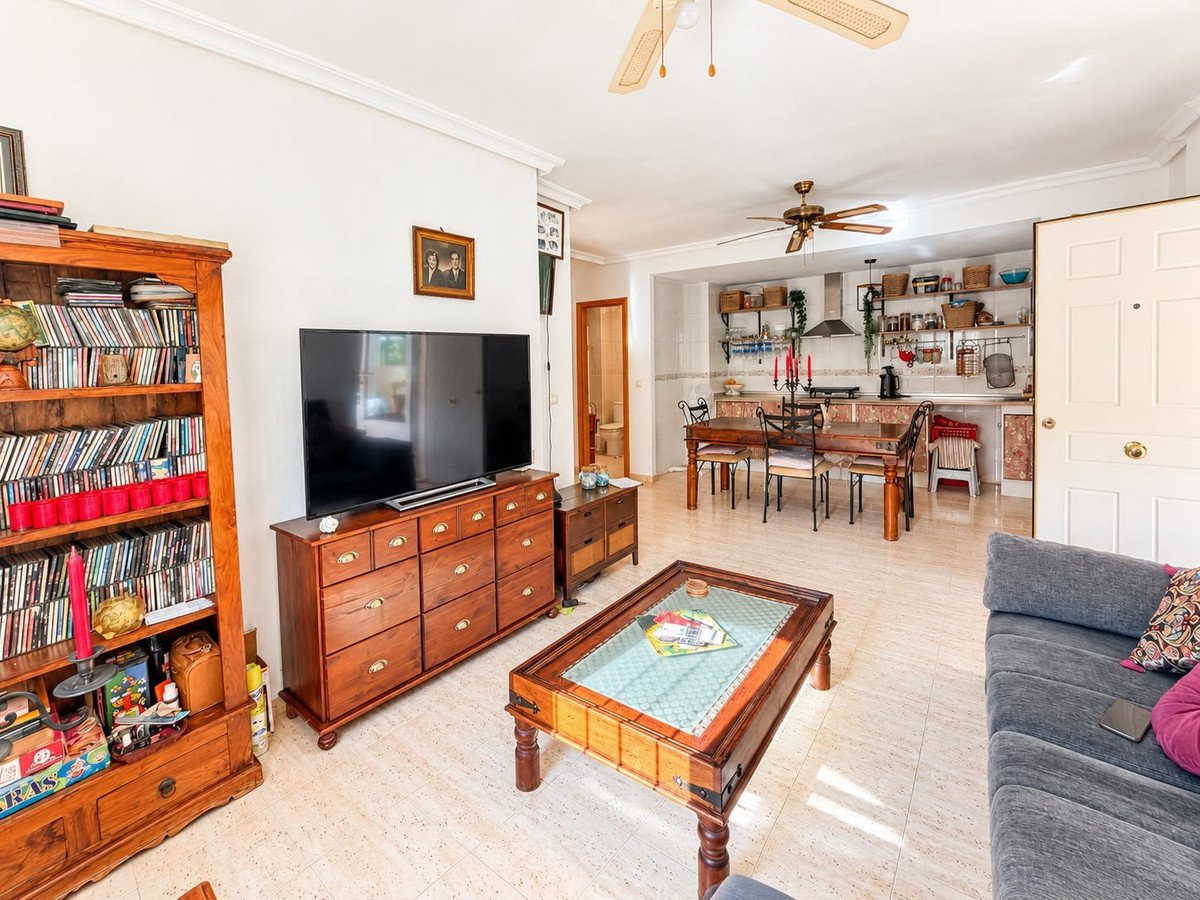 Open concept living, dining, and kitchen area with wooden furniture, a television, and a dining table.