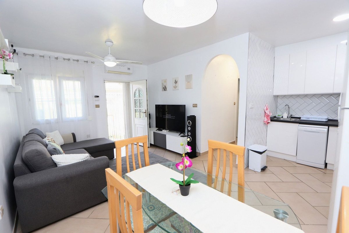 A modern living and dining area with a sectional sofa, dining table, and an open kitchenette.