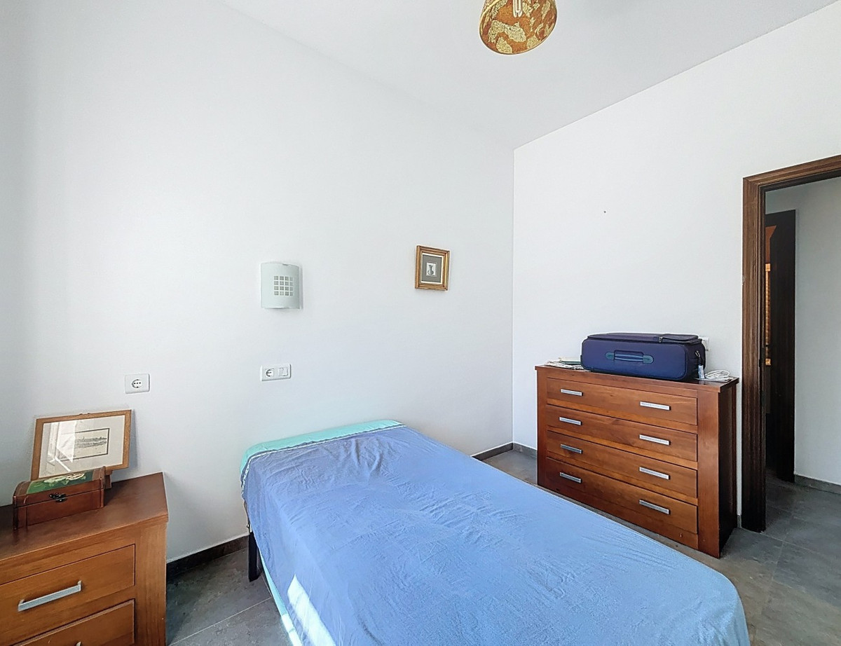 Eenvoudige slaapkamer met minimalistische meubels: bed, commode, nachtkastje.