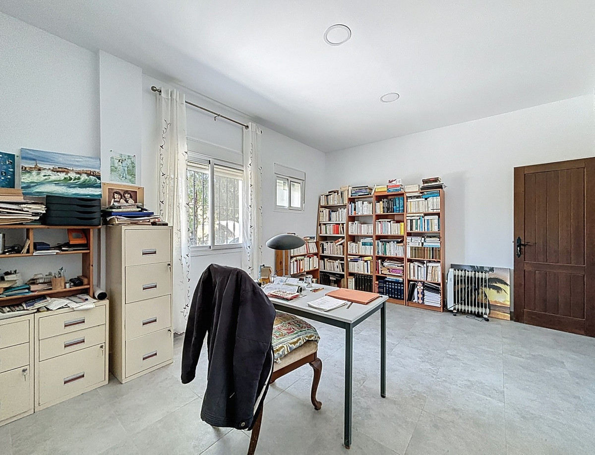 Lichte kantoorruimte met boekenkast en bureau.