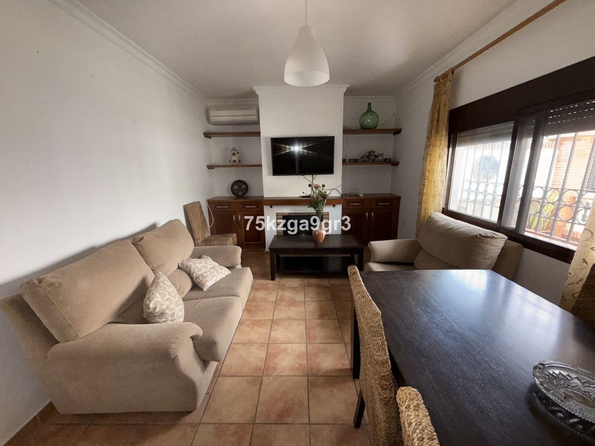 Living room with beige sofa, television, dining table, and large window with curtains