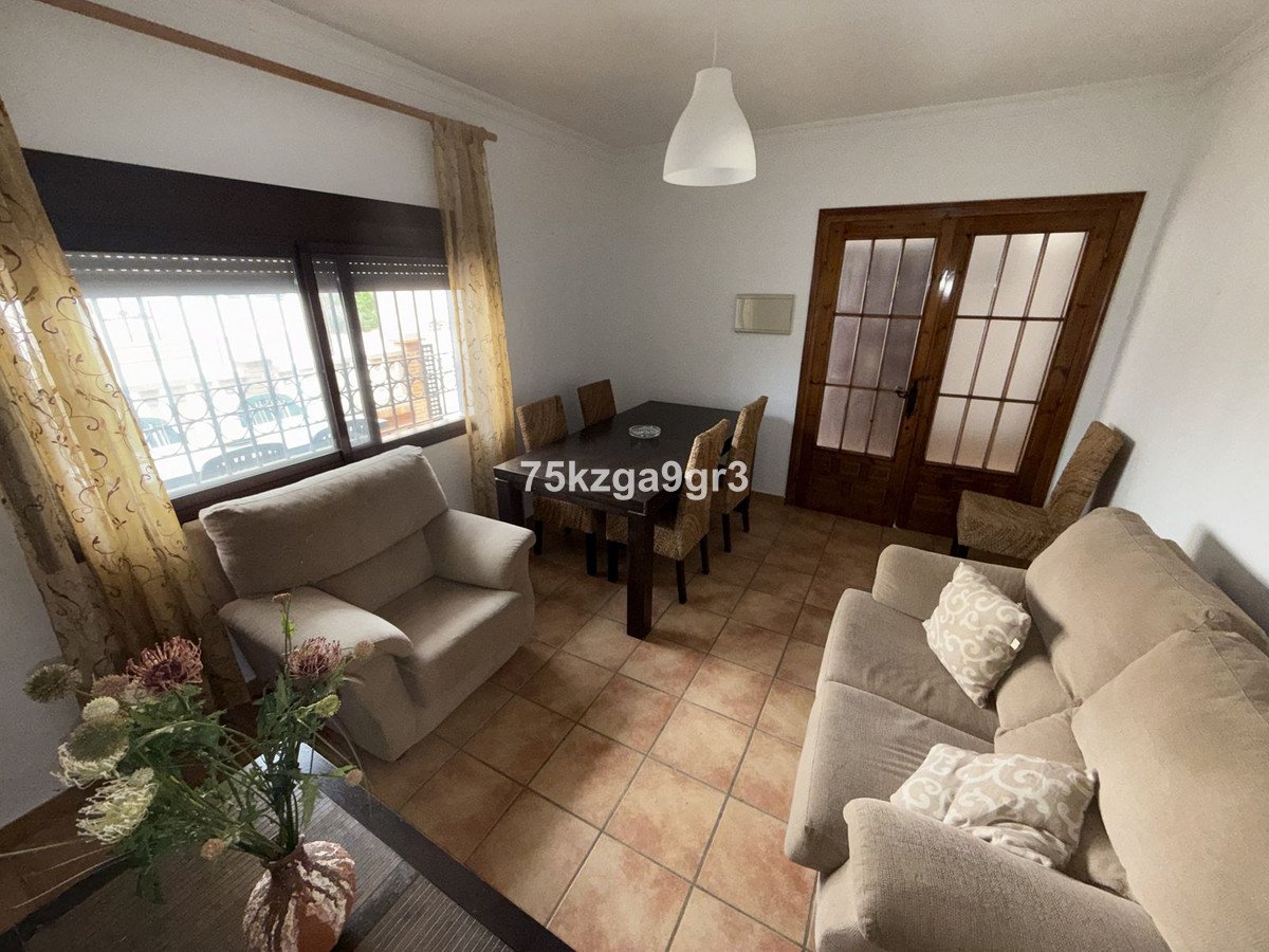 Cozy living room with beige furniture, large window, and dining area
