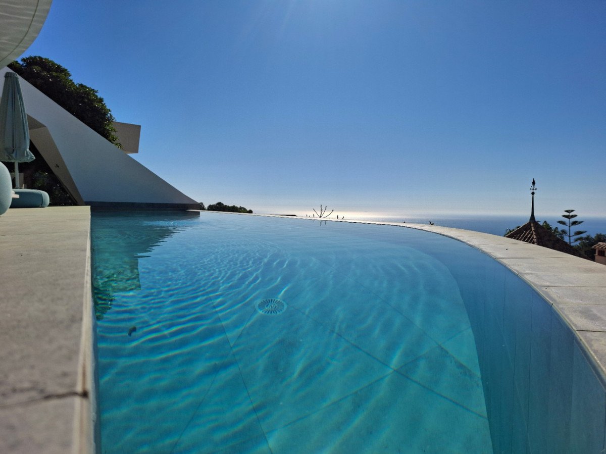 Infinity pool with clear blue water overlooking the sea under sunny sky