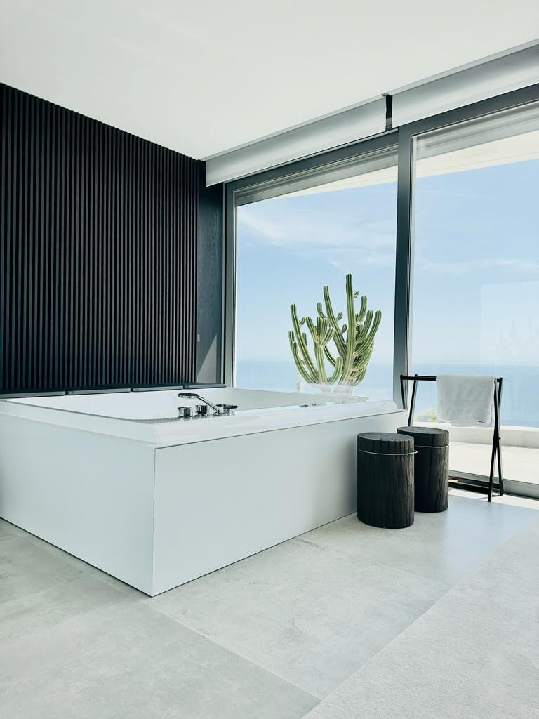Modern bathroom with large tub and ocean view through floor-to-ceiling windows