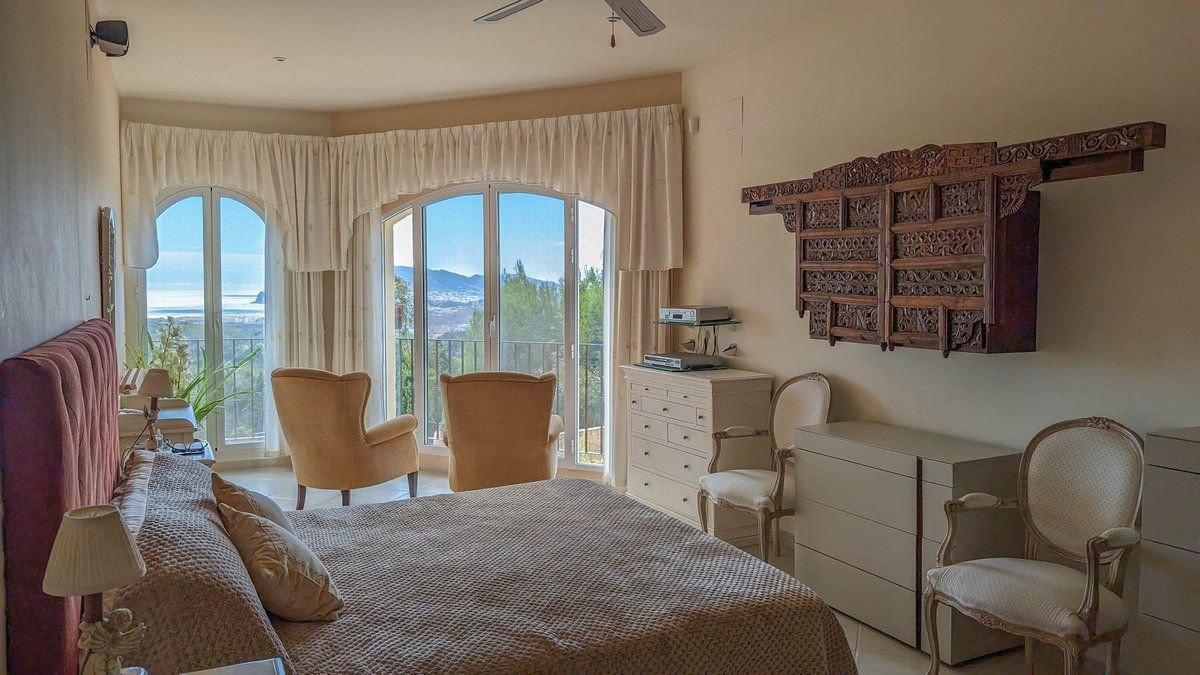 Cozy bedroom with sea view through large arched windows and elegant decor