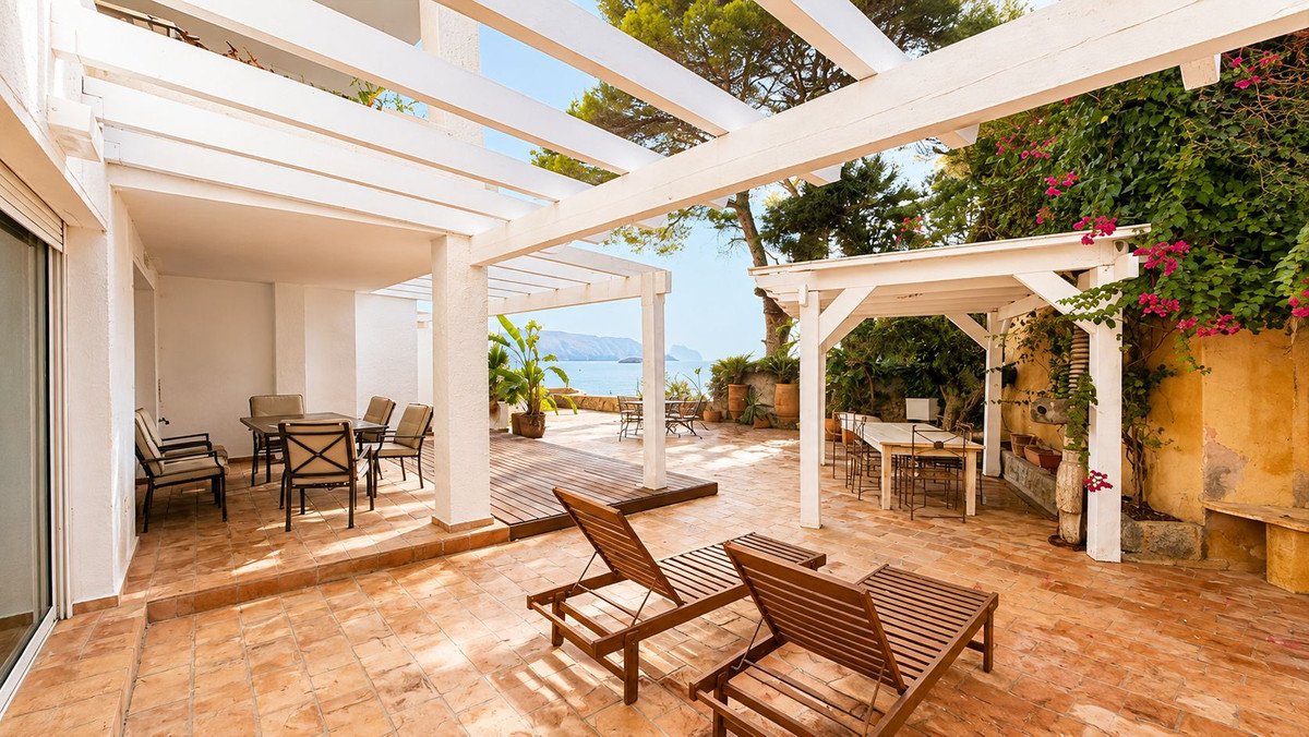 Spacious terrace with outdoor dining furniture, loungers, and a beautiful sea view.