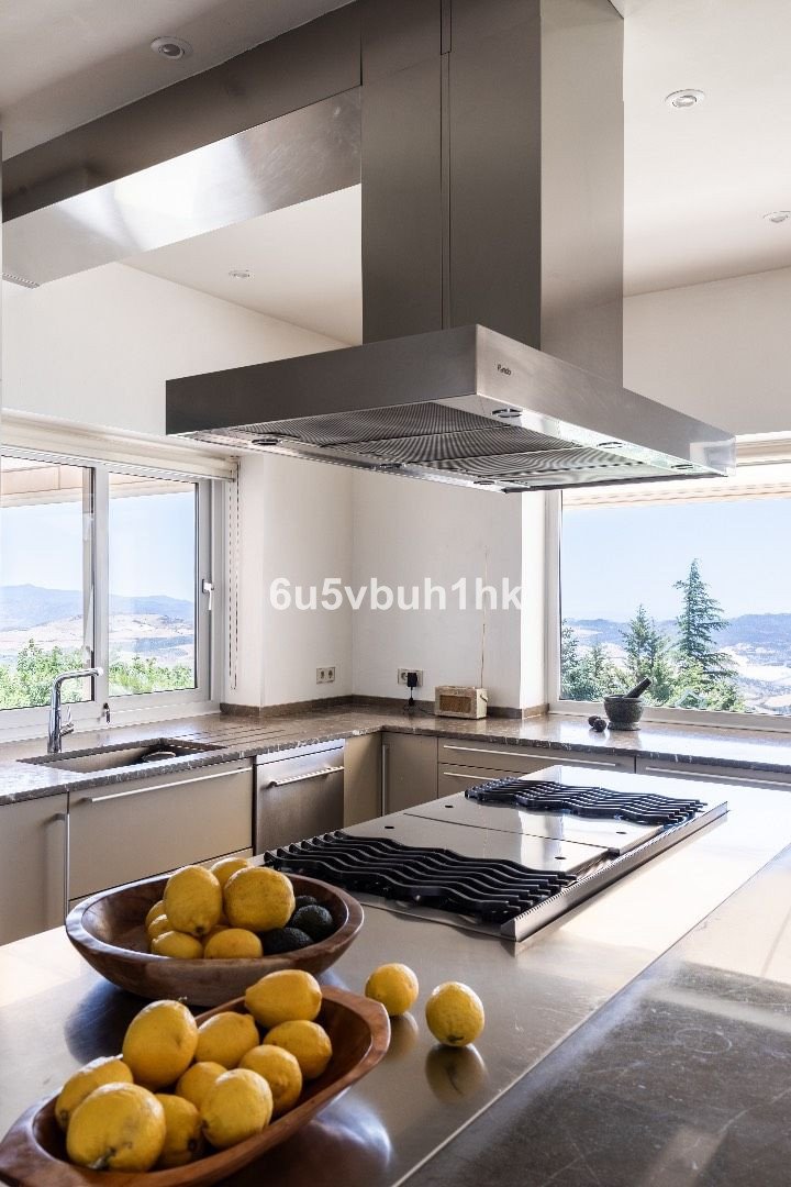 Modern kitchen with stainless steel appliances, granite countertops, and a beautiful mountain view through large windows.