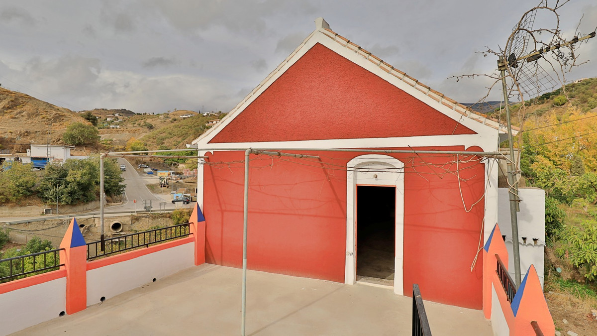 Buitenkant rood huis met terras en uitzicht op de omgeving.