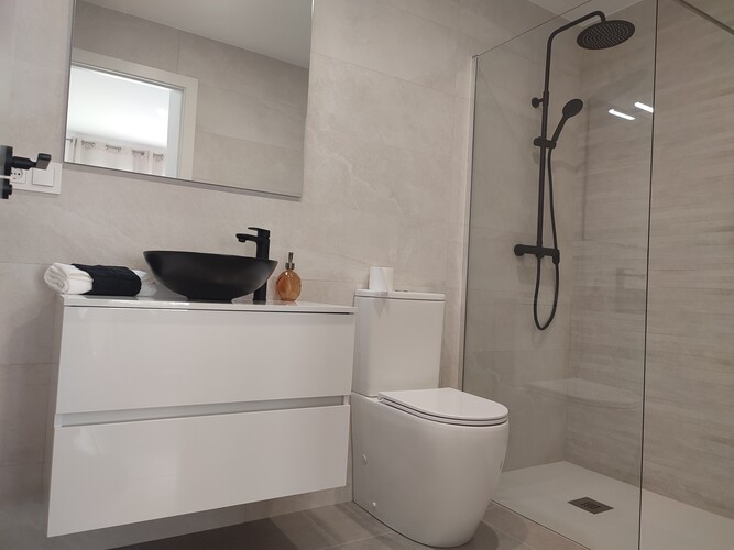 Moderne badkamer met minimalistisch design, zwarte wastafel en inloopdouche.