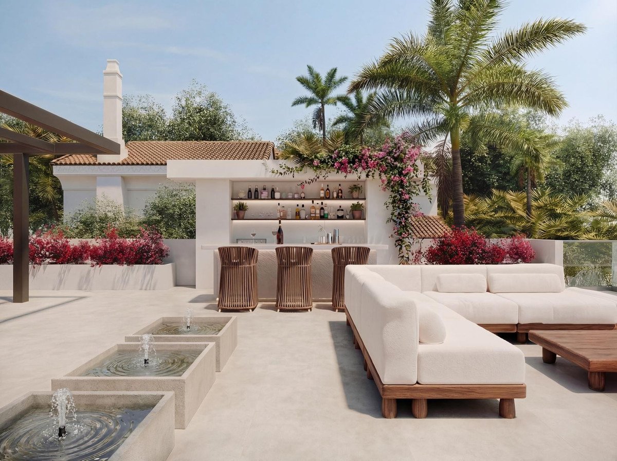 A modern rooftop terrace features a well-stocked bar, comfortable lounge seating, and decorative water fountains, surrounded by lush greenery and palm trees.