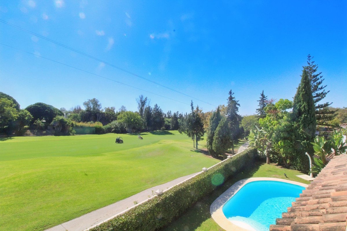 View of a golf course with golf carts and a private swimming pool with bright blue water on a sunny day.