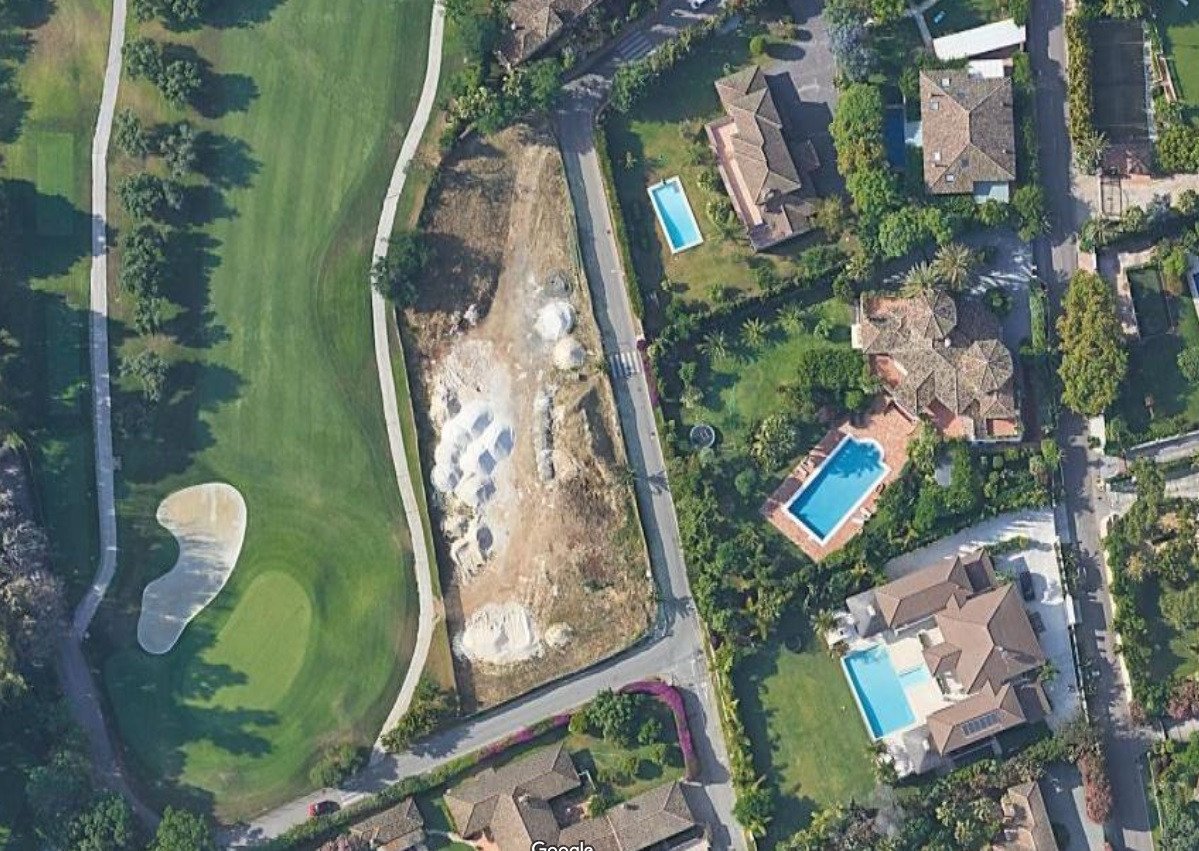 Aerial view of an estate bordering a golf course, featuring multiple swimming pools and lush landscaping.