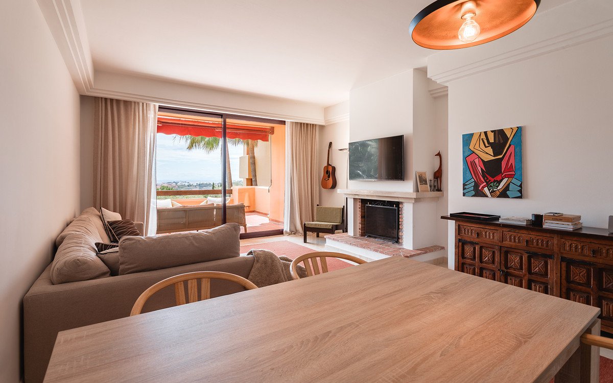 Spacious living room with fireplace, dining table, and balcony view of the sea.