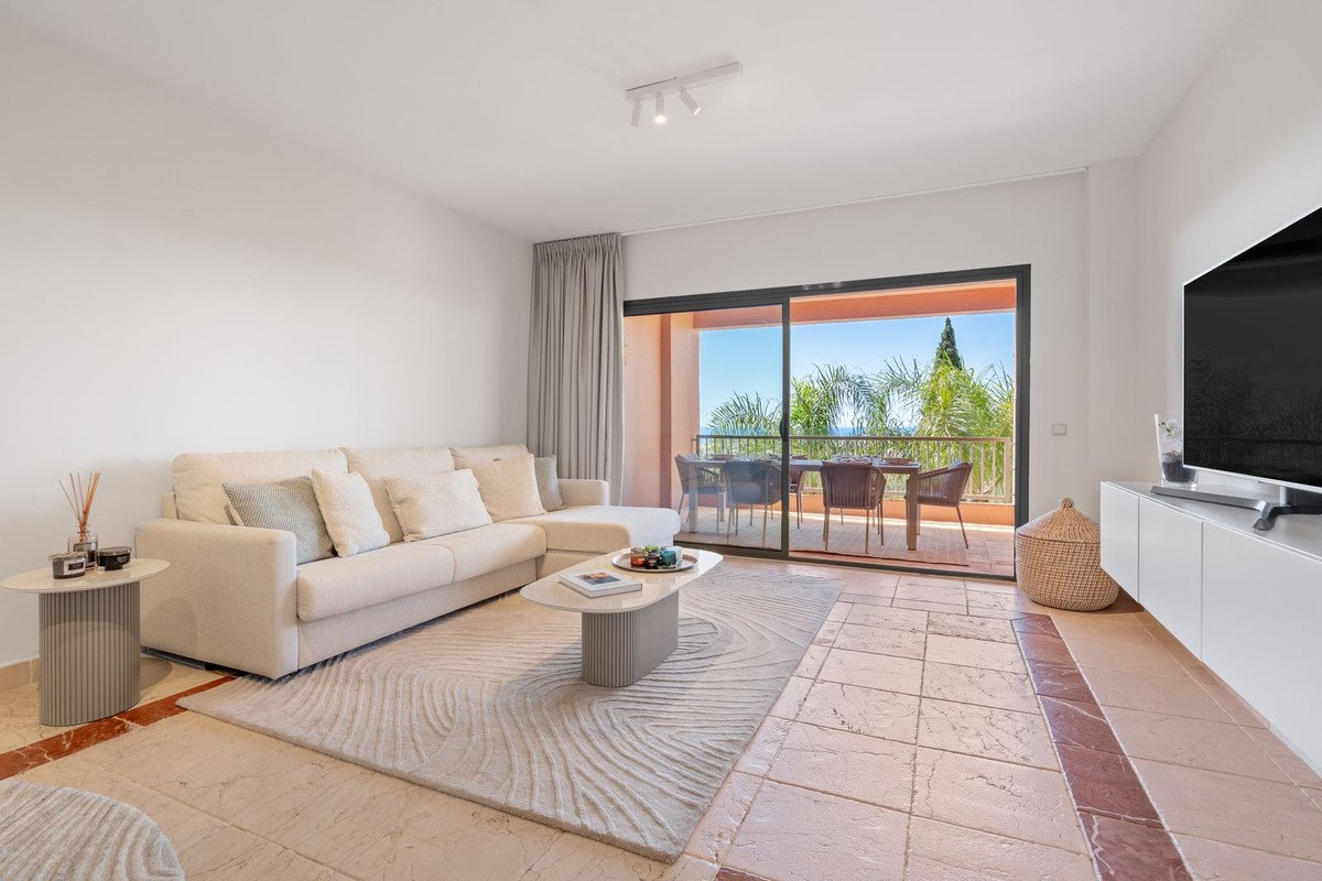 Modern living room with beige sofa, glass doors, and outdoor view