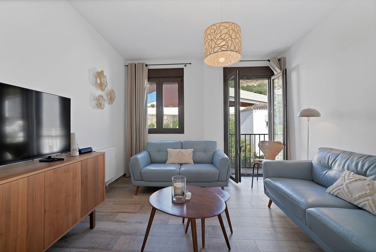 Modern living room with light blue sofas, wooden coffee table, and large windows with a view