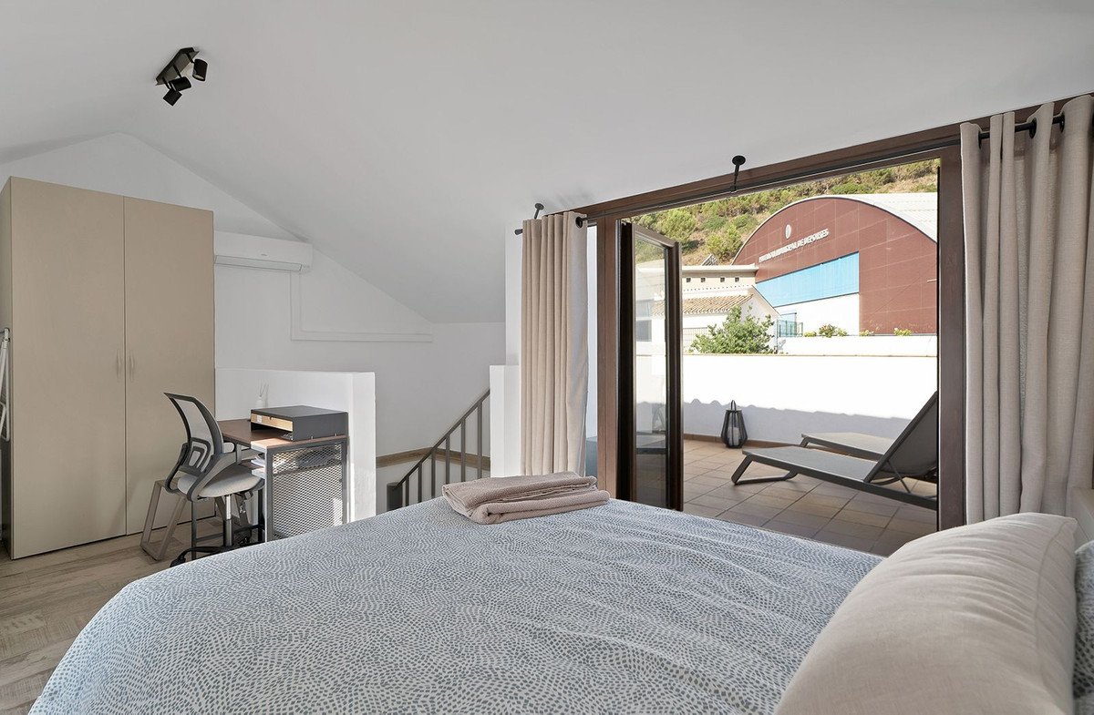 Bedroom with large window overlooking a swimming pool and outdoor lounge area