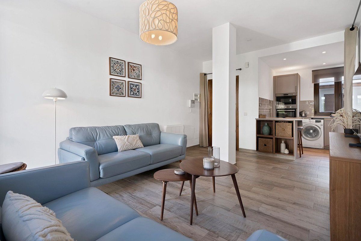Modern living room with blue sofa and wooden coffee table, open to a kitchen area