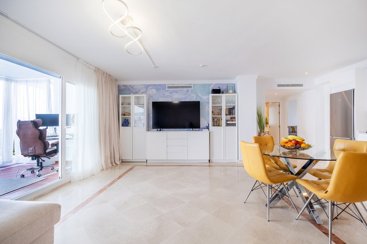 Modern living room featuring a yellow dining set and a large TV