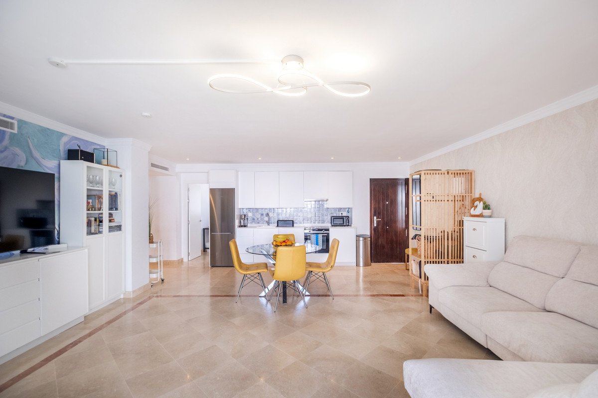Modern open-plan living room with kitchen, dining area, and beige sofa.