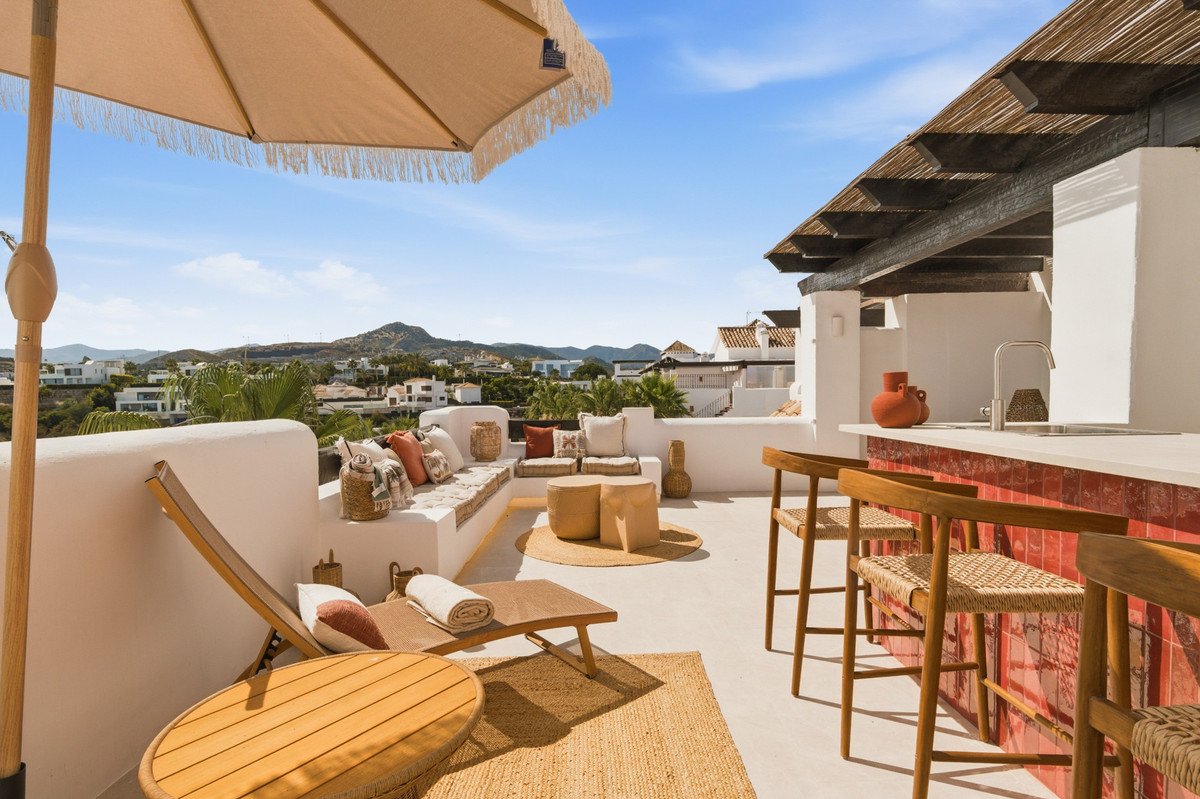 Sunlit rooftop lounge with seating area and scenic view of the town
