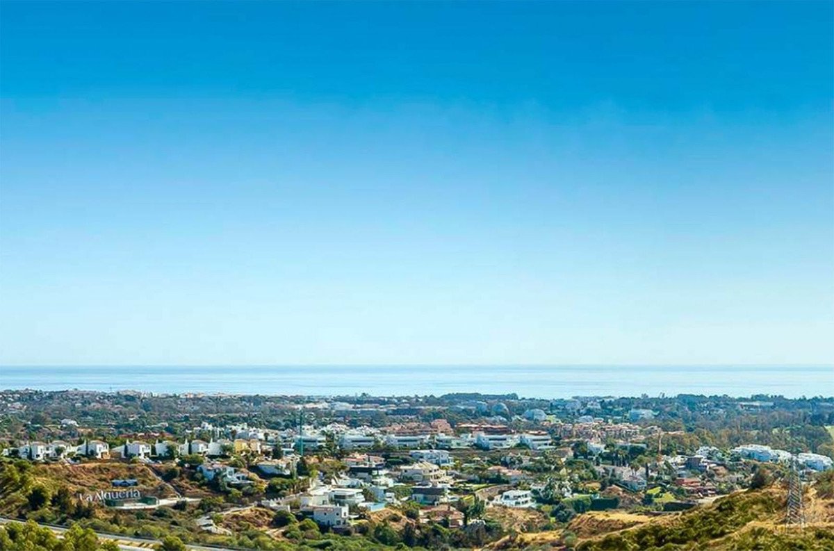 Villa with panoramic sea view, white buildings, green hills, and clear blue sky.
