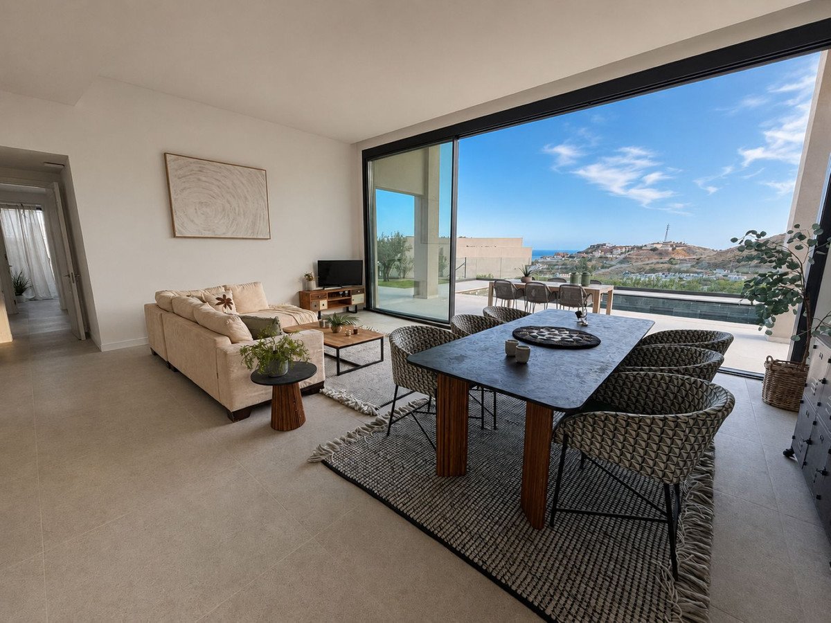 Modern living and dining area with a large sofa, dining table, and expansive sliding doors opening to a scenic sea view.