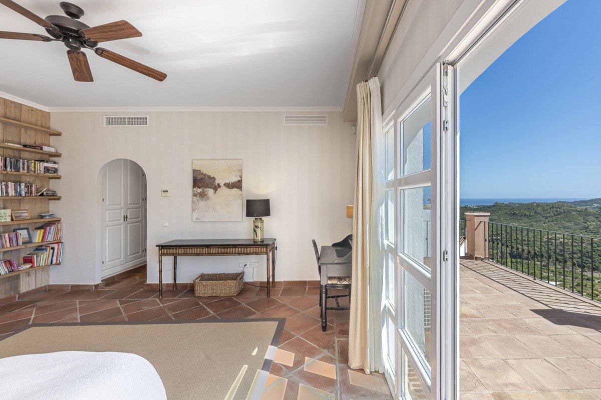 Sunlit master bedroom with large windows overlooking the sea and a balcony