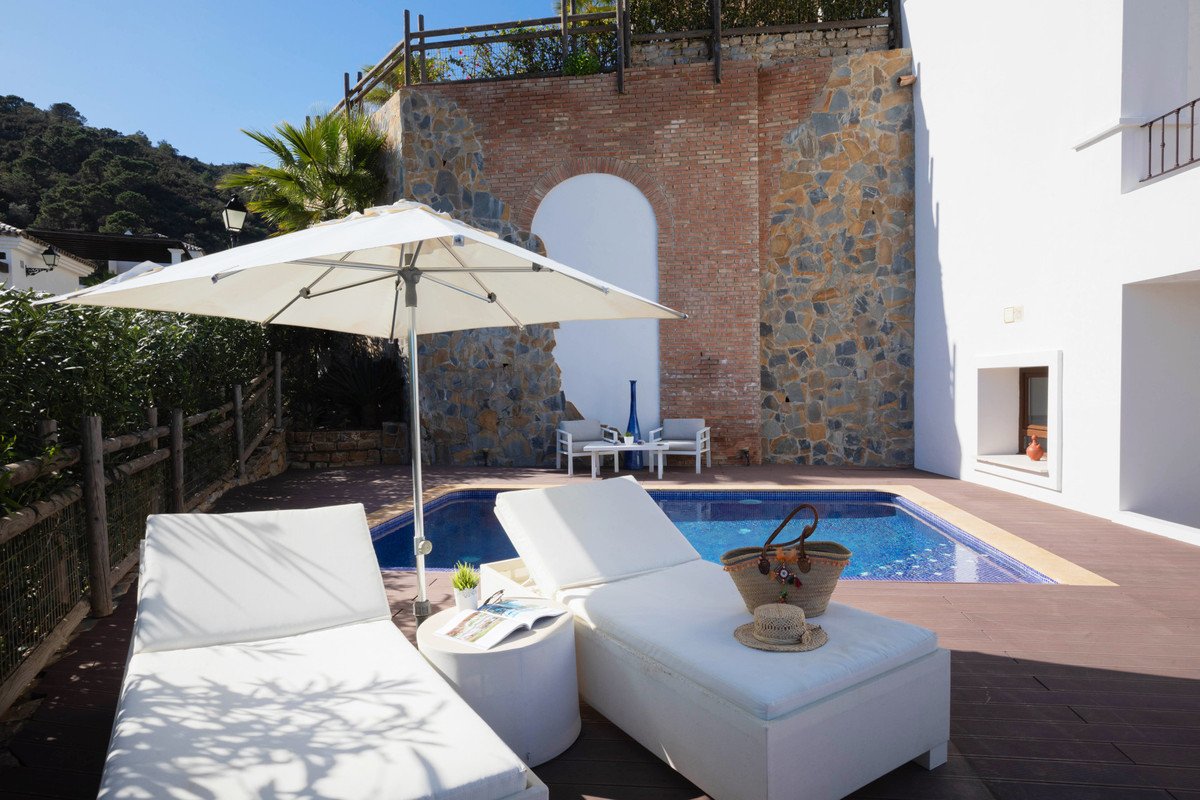 Luxurious outdoor pool area with white lounge chairs and a large umbrella