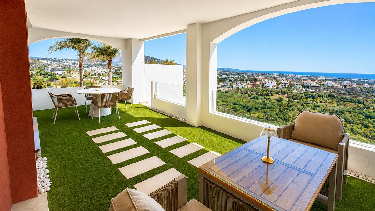 Spacious balcony with artificial grass, outdoor dining, and panoramic sea and mountain views.
