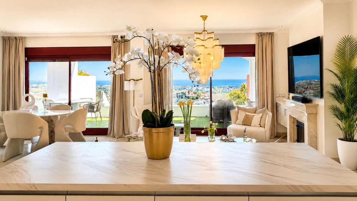 Modern living room with marble island, ocean view, and chandelier.