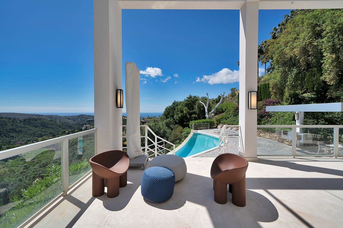 Balcony with seating area overlooking lush green landscape and swimming pool
