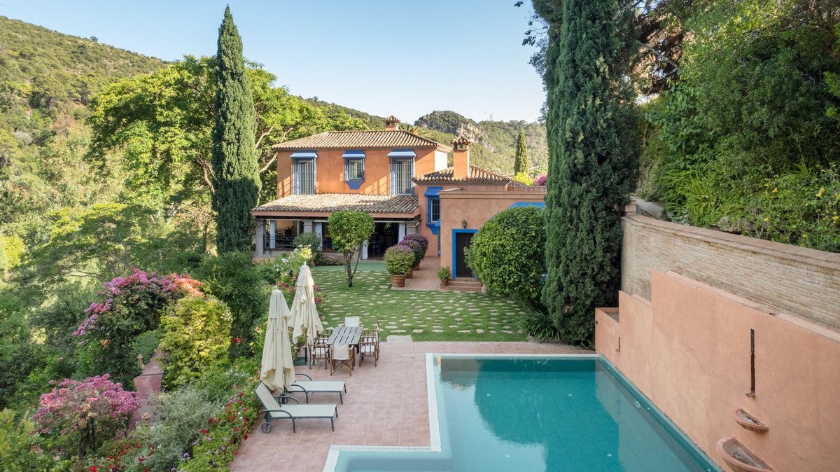 Villa with pool, garden, and mountain views, featuring terracotta tiles and lush greenery.