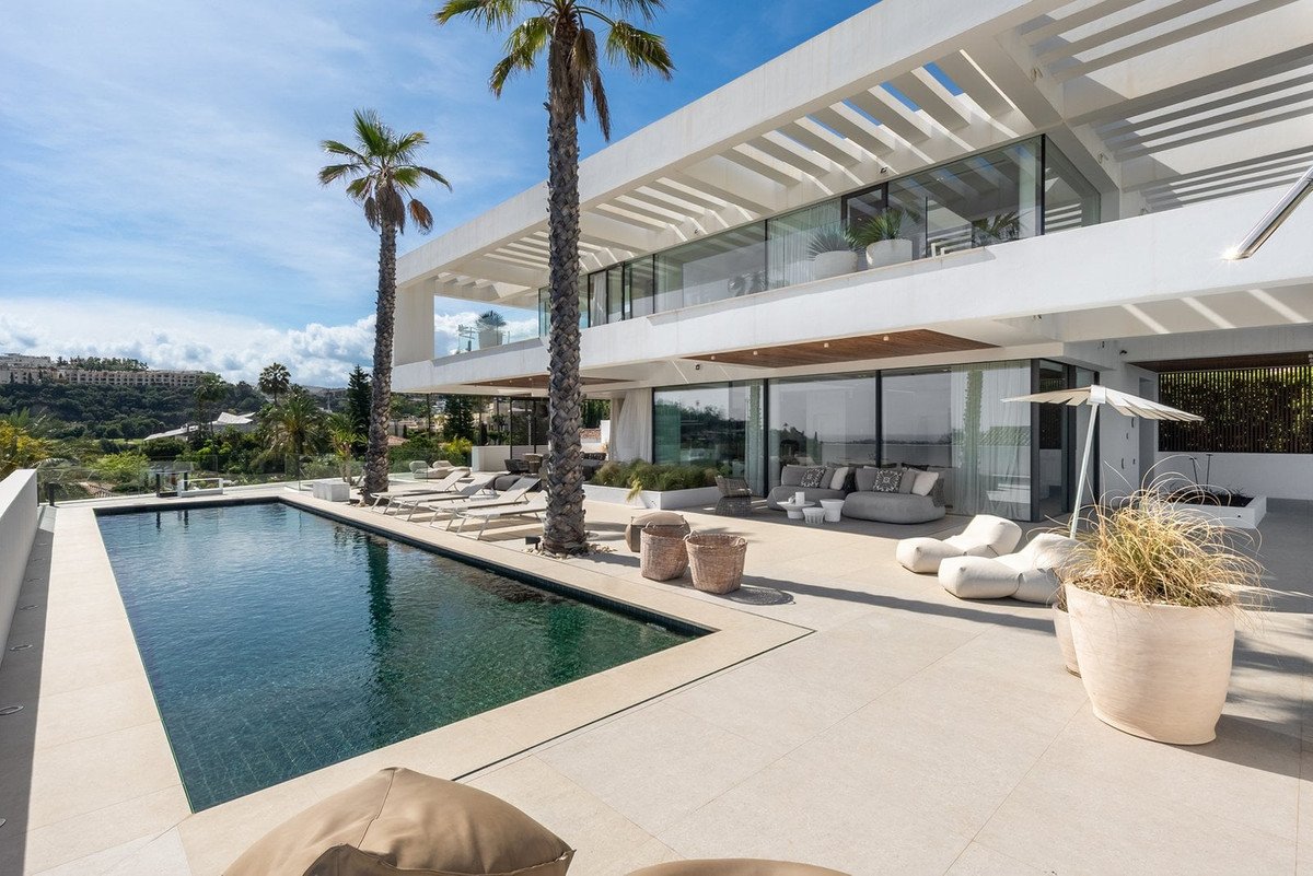 Modern house with a swimming pool, lounge chairs, and palm trees