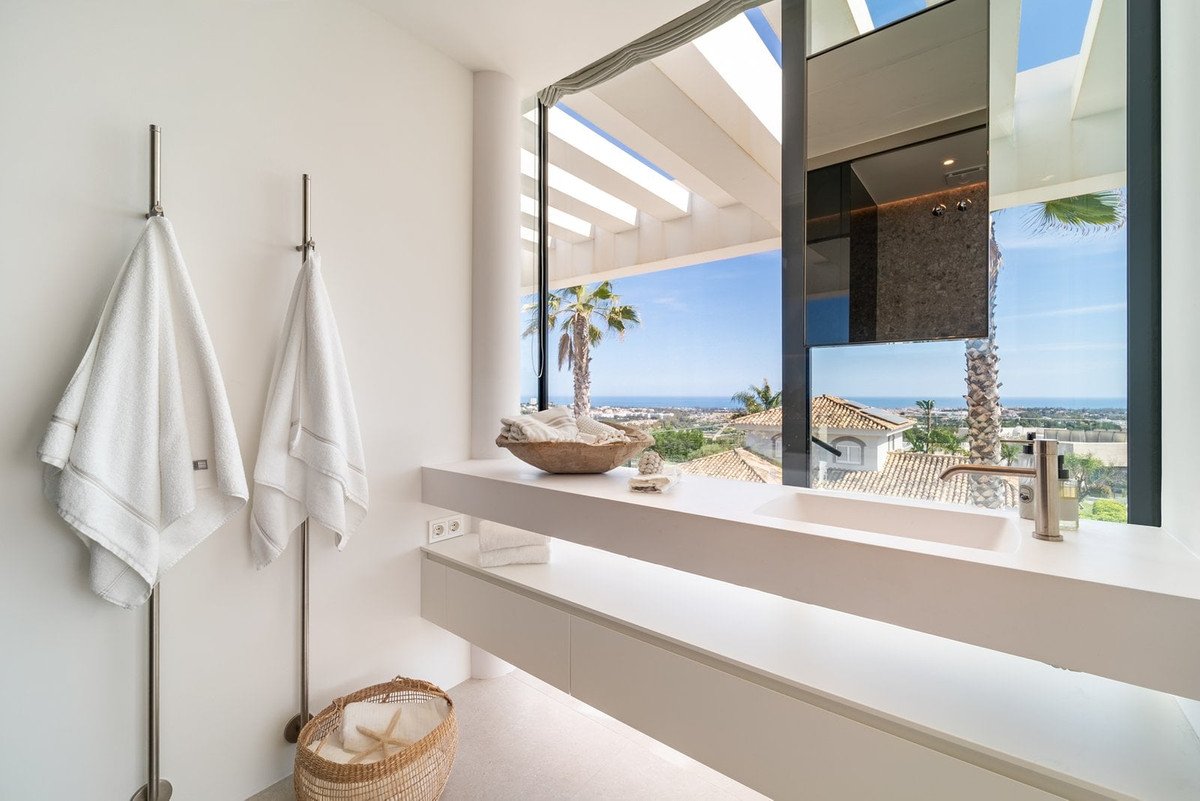 Modern bathroom with large window overlooking the sea and palm trees