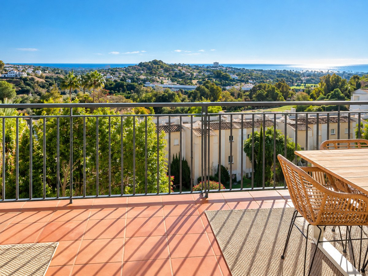A spacious terrace with outdoor dining furniture, offering panoramic sea and landscape views under a clear blue sky.