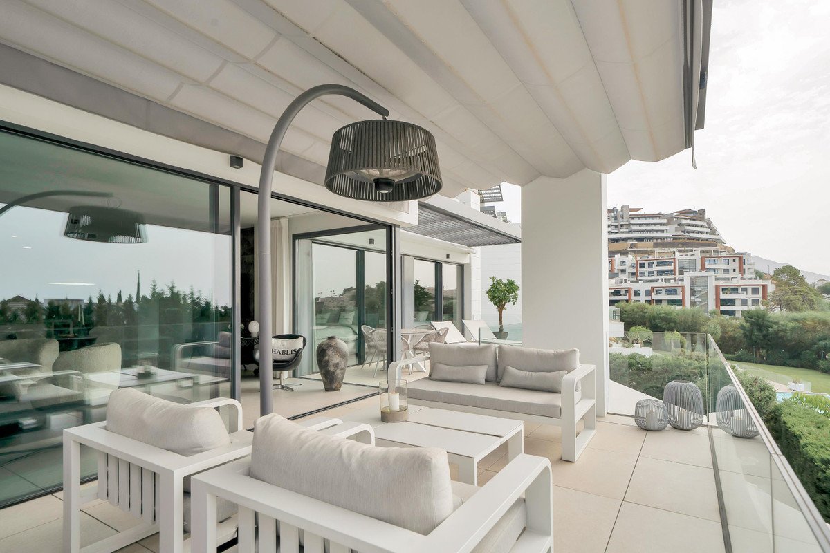 Modern balcony with white furniture, glass railing, and city view.
