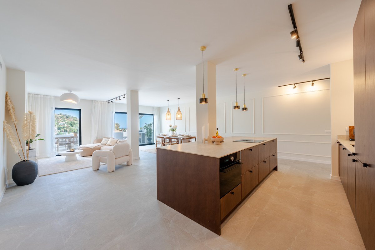 A spacious open-plan living and kitchen area with modern furniture and large windows offering a view of the outdoors.