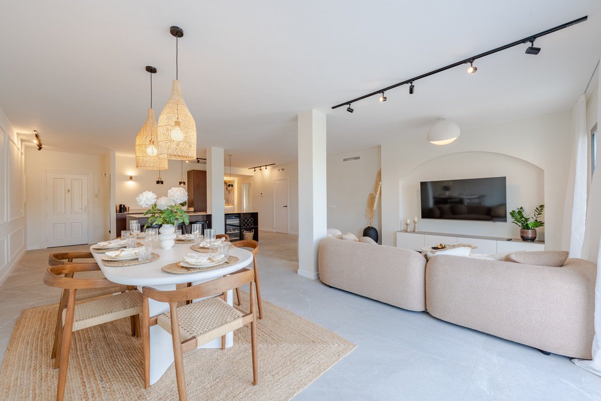 Modern living and dining area with neutral tones, a round dining table, and a sectional sofa facing a TV.
