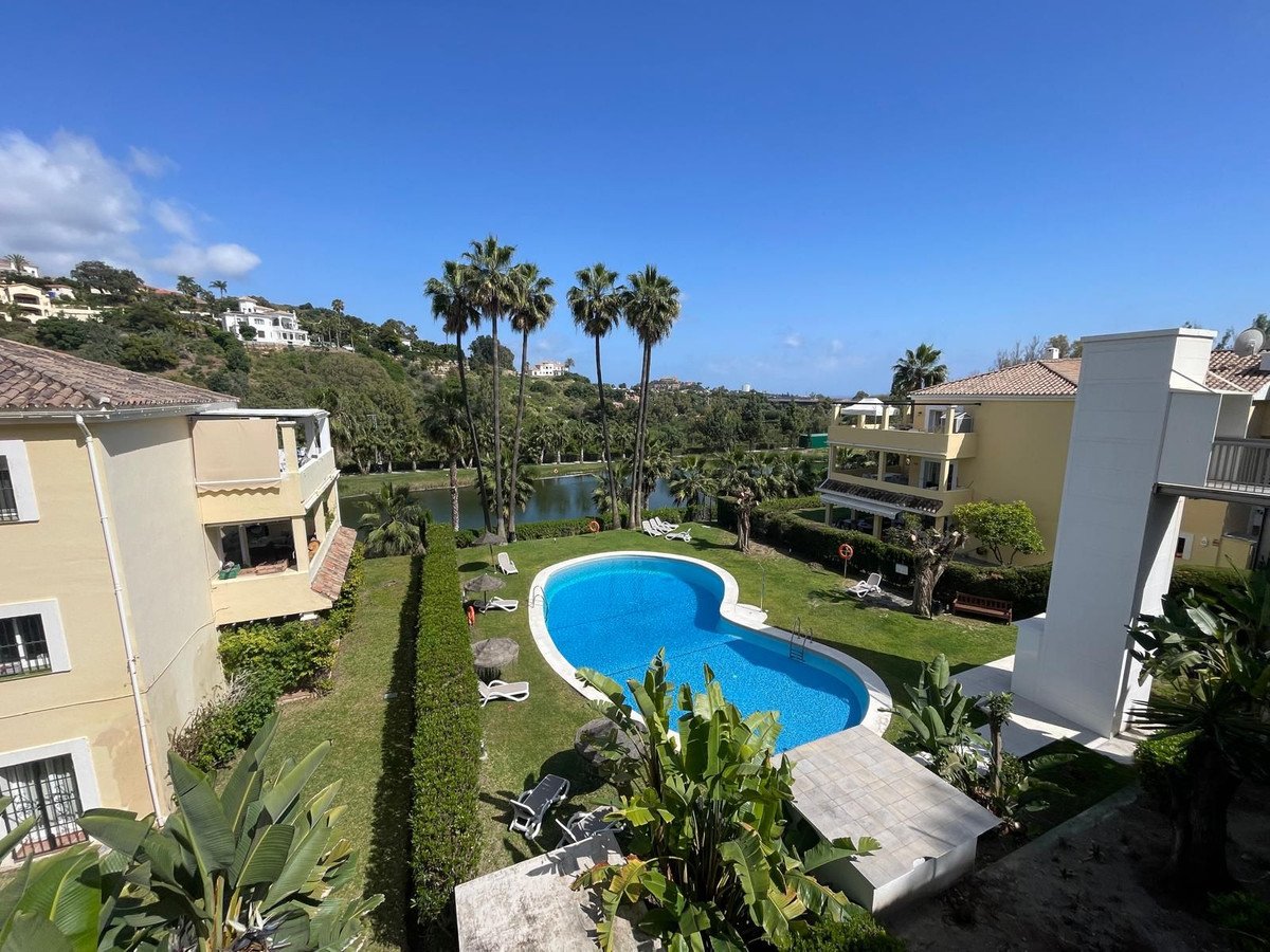 Apartment with pool view, palm trees, and lake in background
