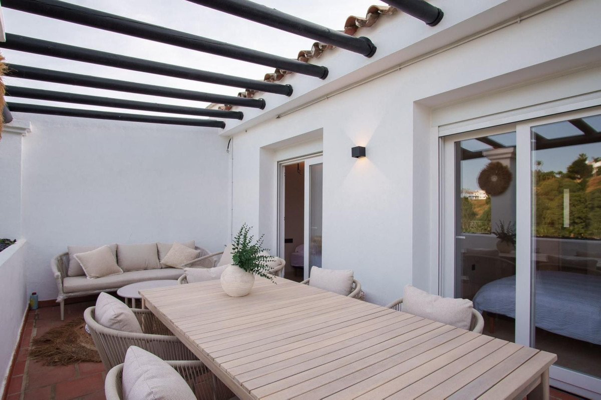 Outdoor terrace with dining table, lounge seating, and sliding glass doors to interior.