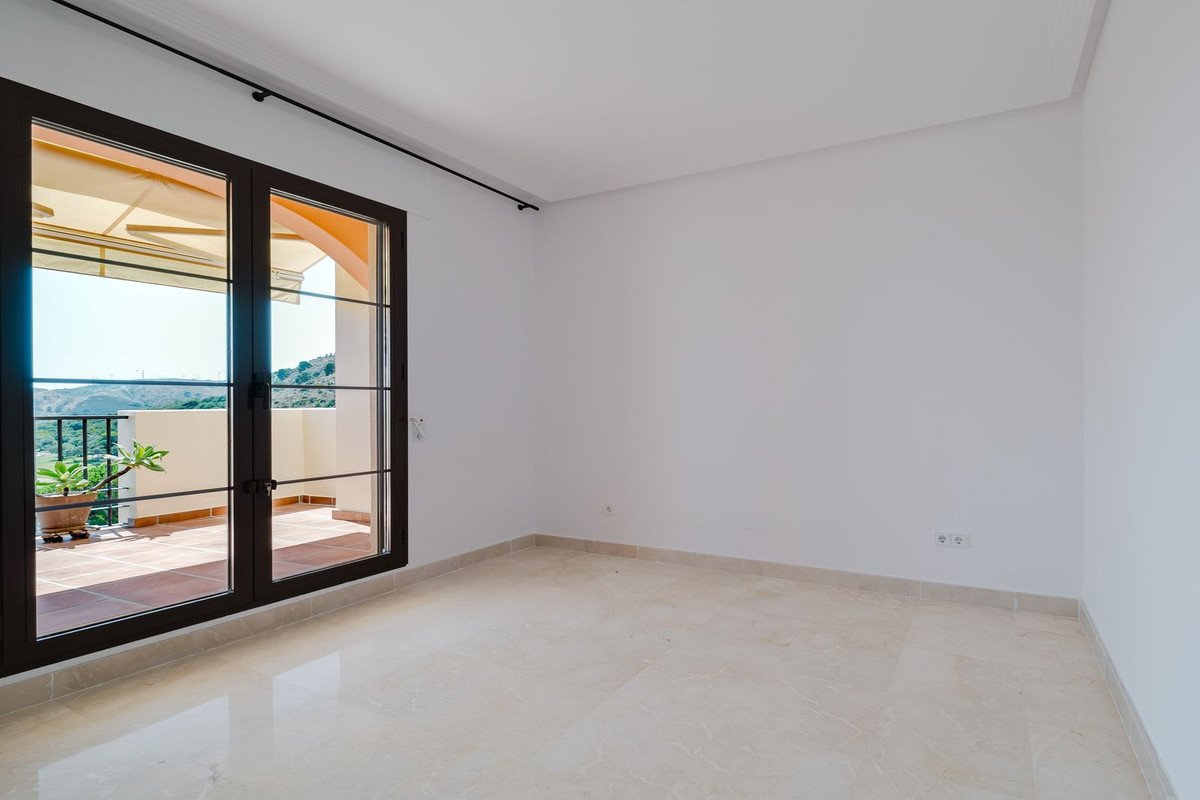 Empty room with double doors leading to a spacious terrace with an awning and a beautiful view of the hills.