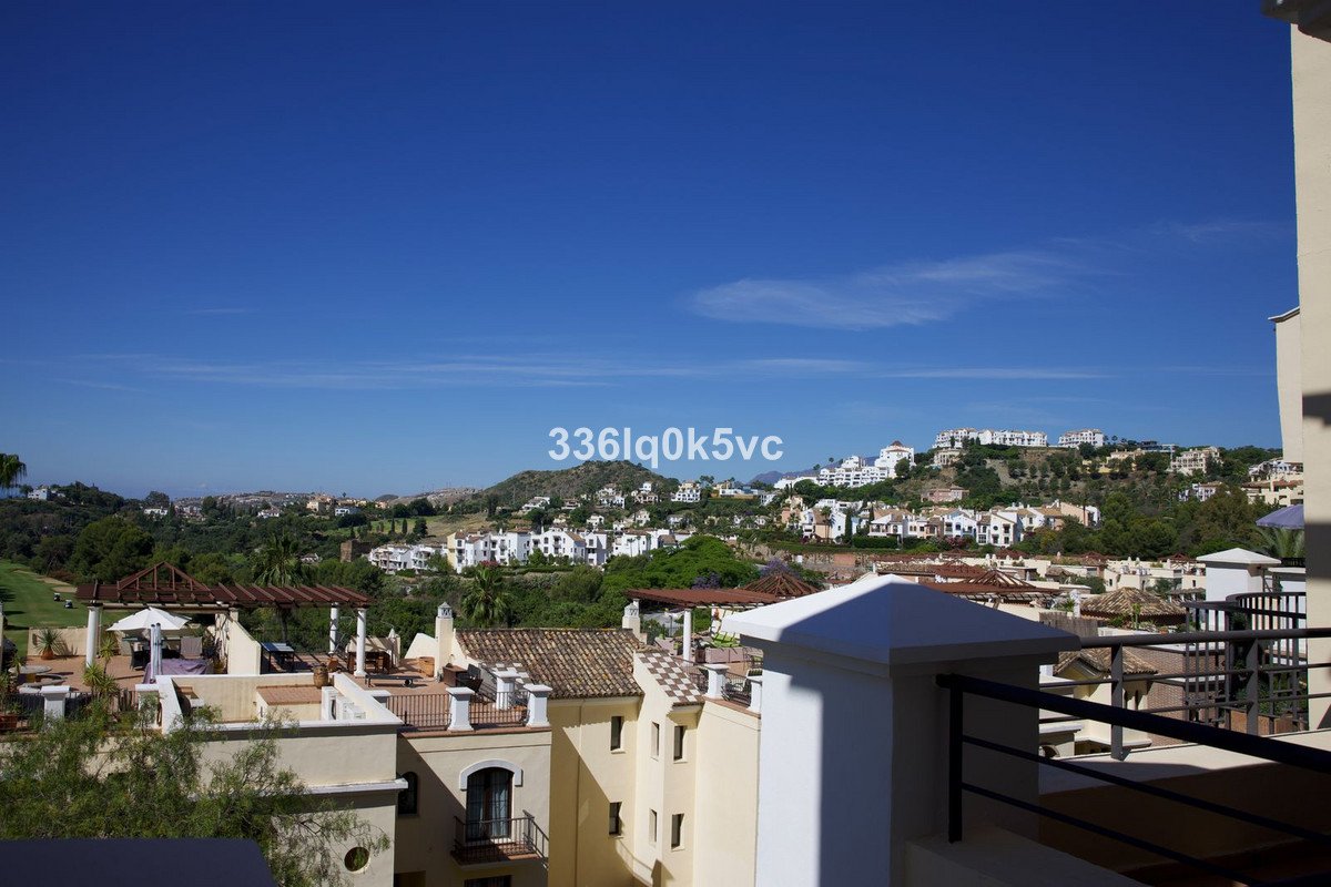 Terrace view overlooking a landscape of white villas on a hillside under a clear blue sky.