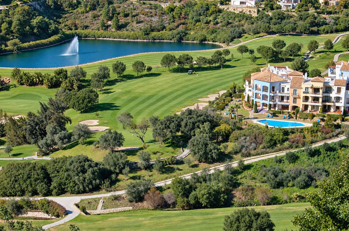 Apartment complex overlooking a golf course with a lake, fountain, and swimming pool.
