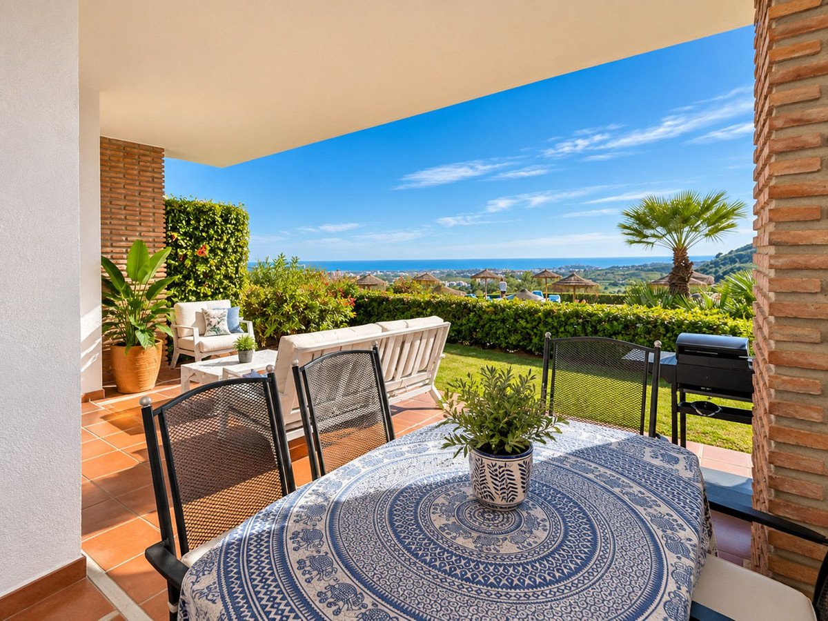 A covered terrace with dining table, chairs, outdoor seating, BBQ, and a stunning sea view.