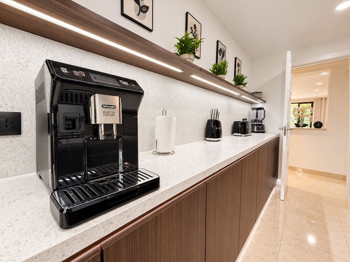 Modern kitchen featuring a black automatic coffee machine, toaster, blender, and stylish cabinetry with under-cabinet lighting.
