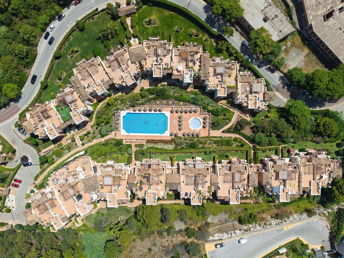 Aerial view of a luxury villa complex with a central pool, terraced gardens, and surrounding greenery.