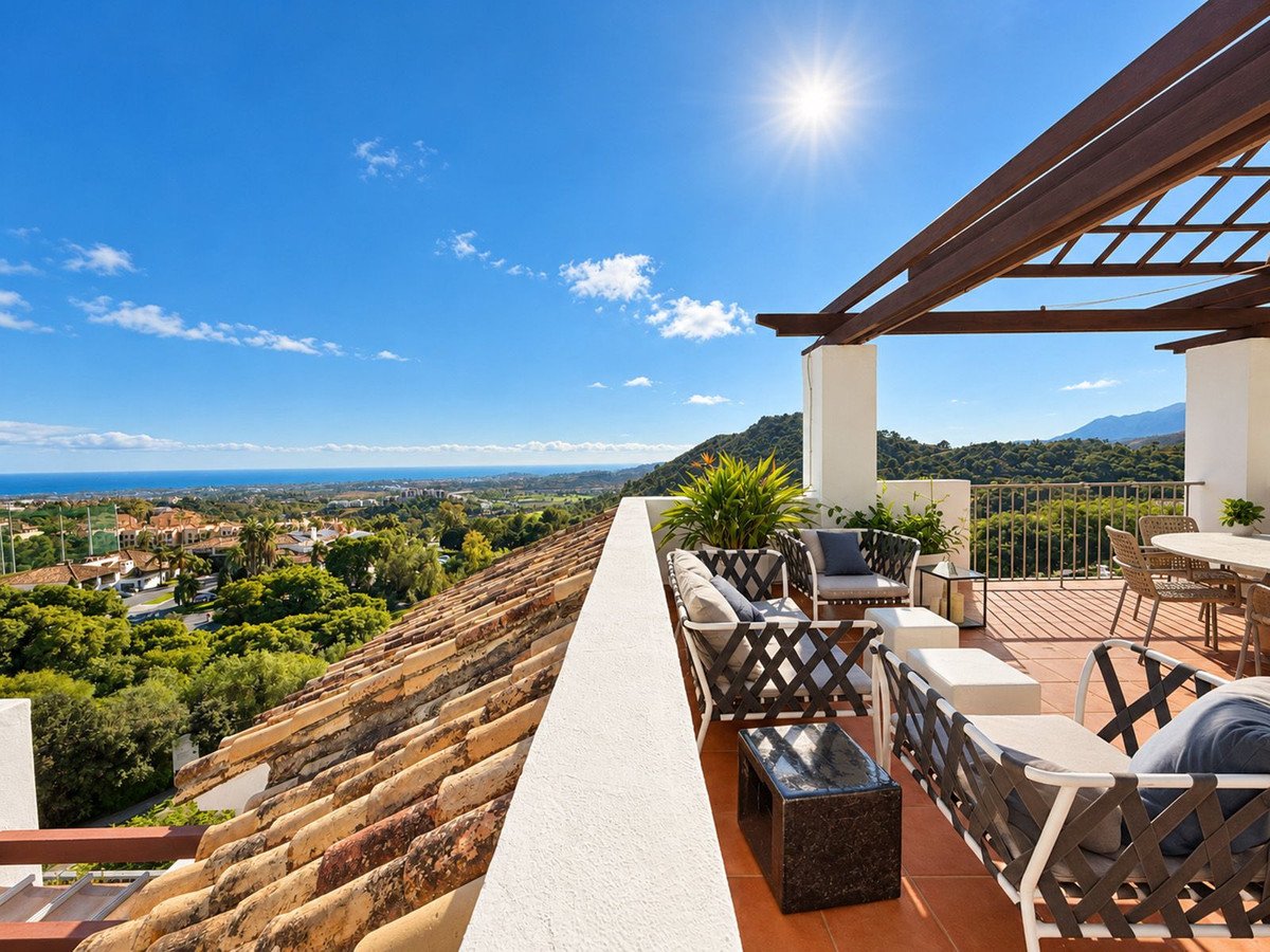 Spacious terrace with sea and mountain views, featuring outdoor seating and dining areas under a pergola.
