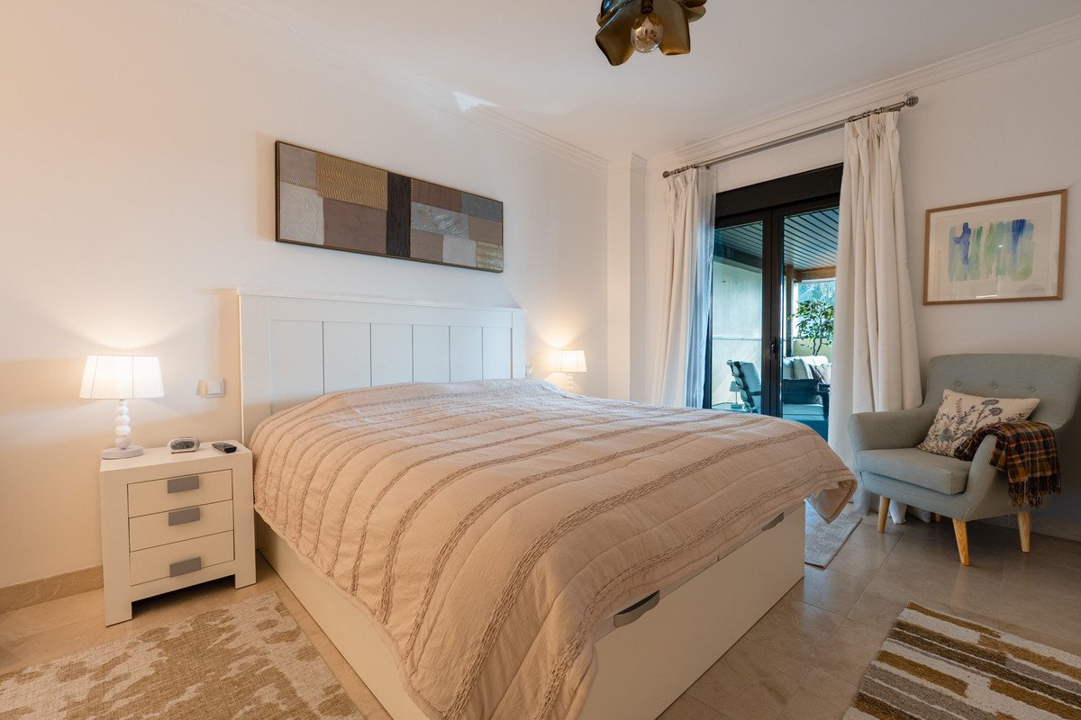Spacious master bedroom with a large bed, nightstands, armchair, and sliding glass doors leading to a terrace.