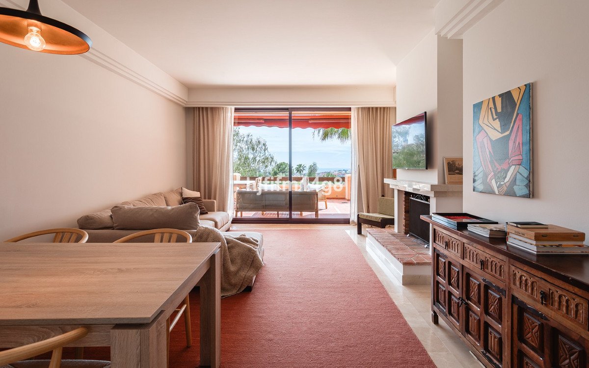 Spacious living room with sofa, fireplace, and balcony access revealing a beautiful sea view.
